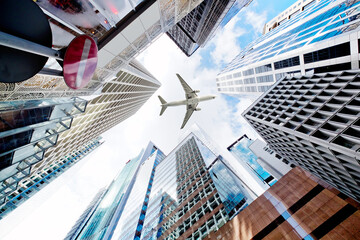 Fototapeta na wymiar Airplane flying over business skyscrapers