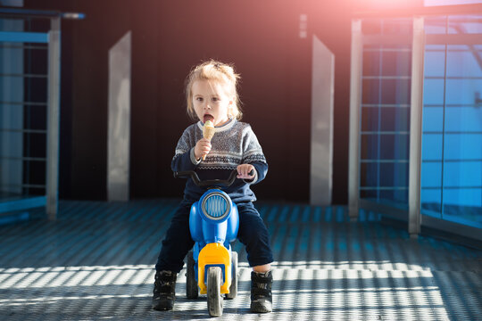 Small Boy Portrait Eating Ice Cream, Sitting On Toy Bike