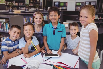 Portrait of smiling schoolkid using digital tablet in library