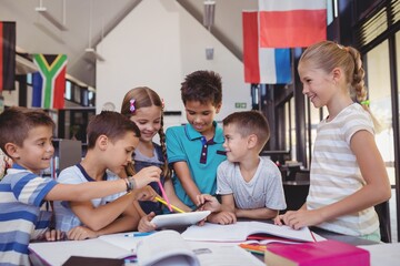 Attentive schoolkids using digital tablet in library