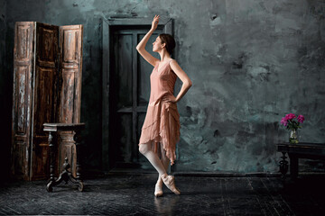 Young and incredibly beautiful ballerina is posing and dancing in a black studio