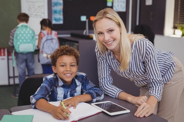 Portrait of smiling teacher helping schoolboy 