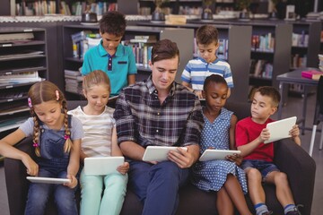 Teacher and schoolkids using digital tablet in library