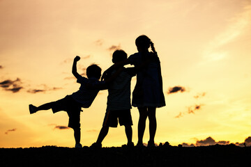 Fototapeta na wymiar Silhouettes of group of children jumping high joyfully on sunset background