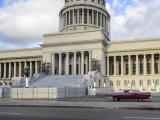 Classic American Cuban taxi car passes in front of the Capitolio building in Central Havana.