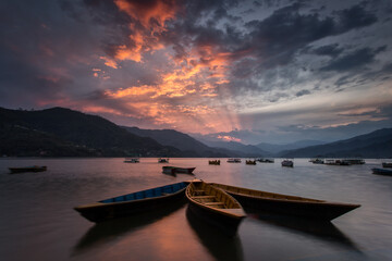 Colourful boats on lake in Pokhara with beautiful sunset in background