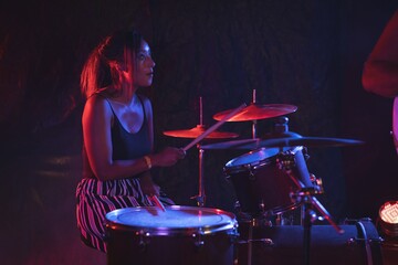 Fototapeta na wymiar Female drummer practicing in nightclub
