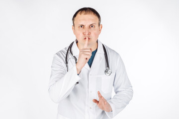 Fototapeta premium portrait of a male doctor doing shush gesture as silence or secret