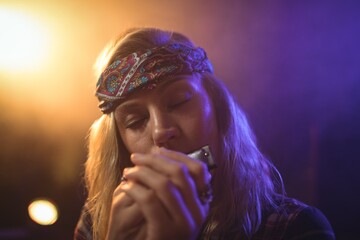 Beautiful female musician playing harmonica in nightclub - obrazy, fototapety, plakaty