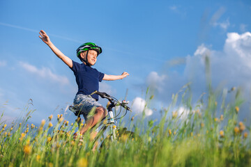 Happy boy ride a bicycle without hands and enjoy with sunlight