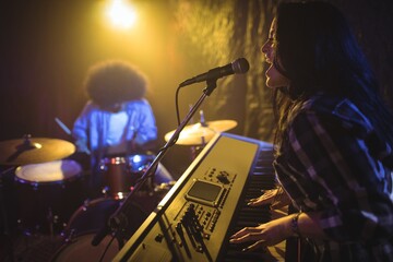 Fototapeta na wymiar Female playing piano while performing in nightclub