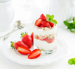 Dessert in a glass with granola, yogurt and strawberries. Useful breakfast.