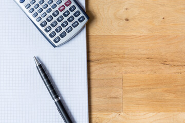 Work desk with note pad, calculator and biro on wooden table