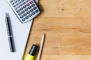 Work desk with note pad, calculator and biro on wooden table