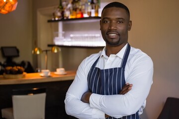 Portrait of waiter standing with arms crossed in restaurant