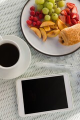 Overhead view of digital tablet by coffee cup and fruits