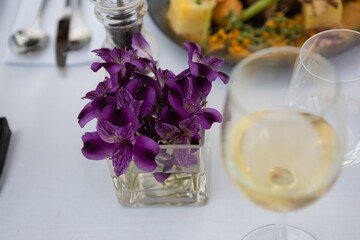Obraz na płótnie Canvas Flower vase by white wine on table in restaurant