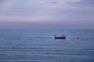 Fototapeta premium A boat in a Mediterranean beach of Ionian Sea at sunset - Bova Marina, Calabria, Italy