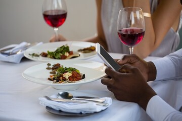 Hands of man using mobile phone while sitting at restaurant