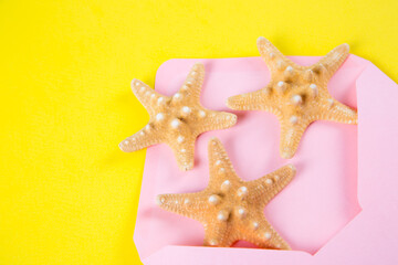 Pink envelope with three starfishes on colored yellow background