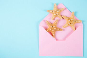 Fototapeta na wymiar Pink envelope with three starfishes on colored mint blue background