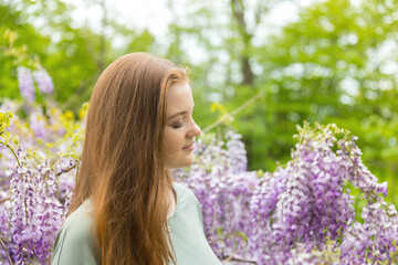 Natural beauty: red hair girl and freckles glow skin on the purple flowers background