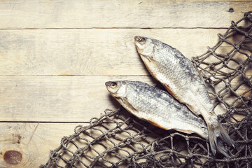Dried and salty fish and fishing nets on the wooden background. Still-life and objects.