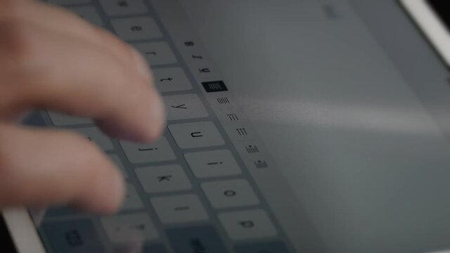 Man typing text on electronic tablet using screen keyboard. Hands close-up.