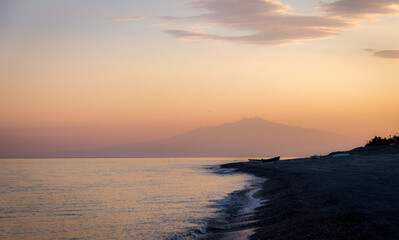 Sunset on a Mediterranean beach of Ionian Sea with Mount Etna Volcano on background - Bova Marina, Calabria, Italy