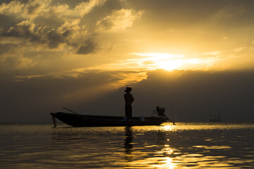 Silhouettes of fisherman at the lake with sunset, Thailand.