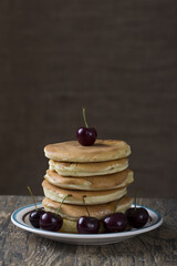 Stack of pancakes with berries on a brown wood table