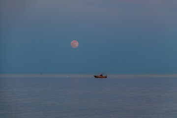 A boat and a rising moon in a Mediterranean beach of Ionian Sea - Bova Marina, Calabria, Italy