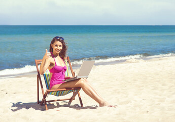 Young and beautiful woman working on a laptop on a beautiful beach. Freelance concept.