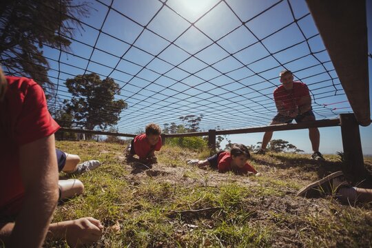 Kids crawling under the net during obstacle course training