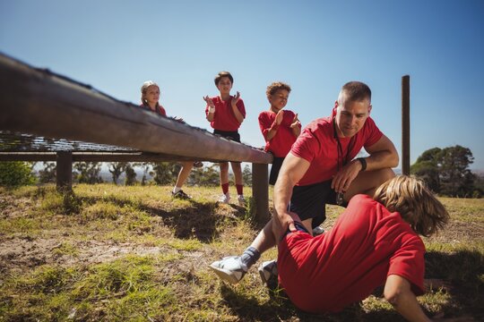Trainer assisting kids in the obstacle course training