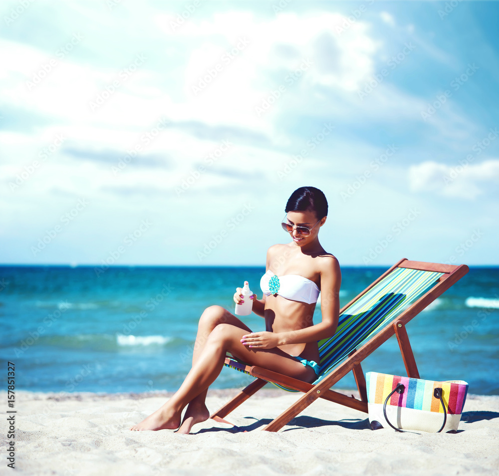 Wall mural attractive young girl in bikini sunbathing on beach. traveling, holiday, vacation concept.