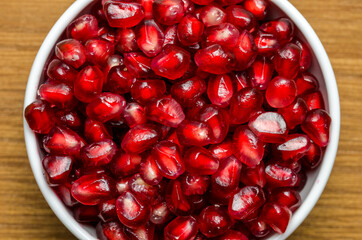 Grains Of Pomegranate In A White Bowl On A Wooden Board. Close-Up. Free Space For Text. Top View. Marco.