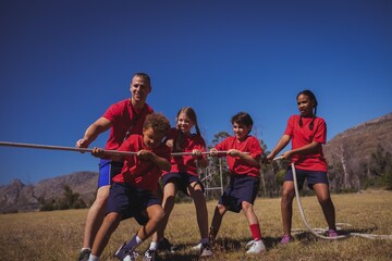 Trainer assisting kids in tug of war during course