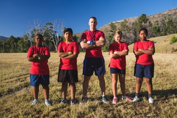 Trainer and kids standing with arms crossed in the boot camp