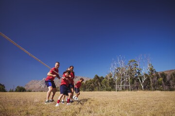 Trainer assisting kids in tug of war during obstacle