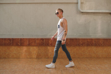Hipster handsome man guy in stylish summer clothes in the street in sunglasses