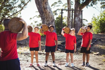 Trainer and kids carrying wooden log