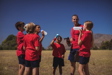 Trainer and kids drinking water in the boot camp