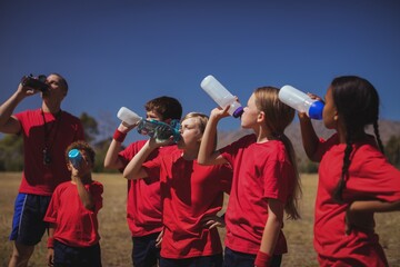 Trainer and kids drinking water in the boot camp - Powered by Adobe