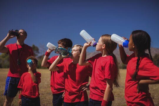 Trainer and kids drinking water in the boot camp