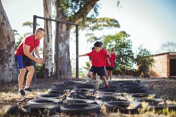 Trainer instructing kids during tires obstacle course training - Powered by Adobe