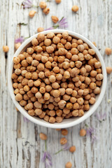 Chickpeas in a white bowl on a wooden table, top view