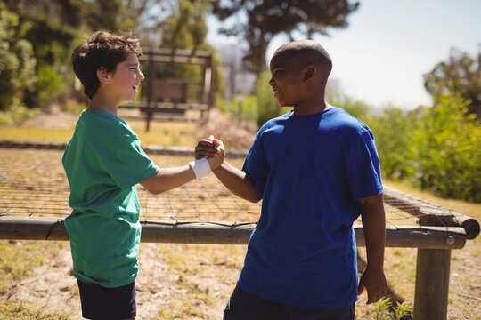 Happy friend holding hands during obstacle course - Powered by Adobe