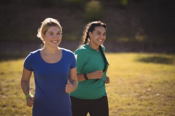 Happy friends running on grass during obstacle course