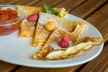 Crepes with jam, berries and sugar powder. Homemade pancakes, delicious breakfast